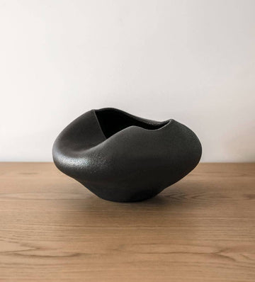 Black ceramic bowl on a wooden surface with a white background