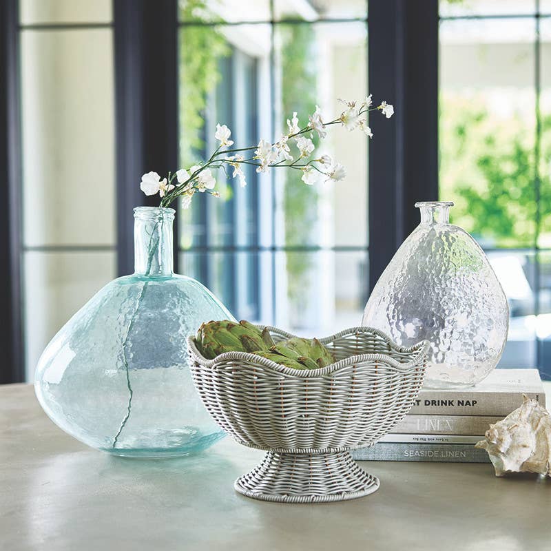 Decorative setting with glass vases and a wicker basket on a table.