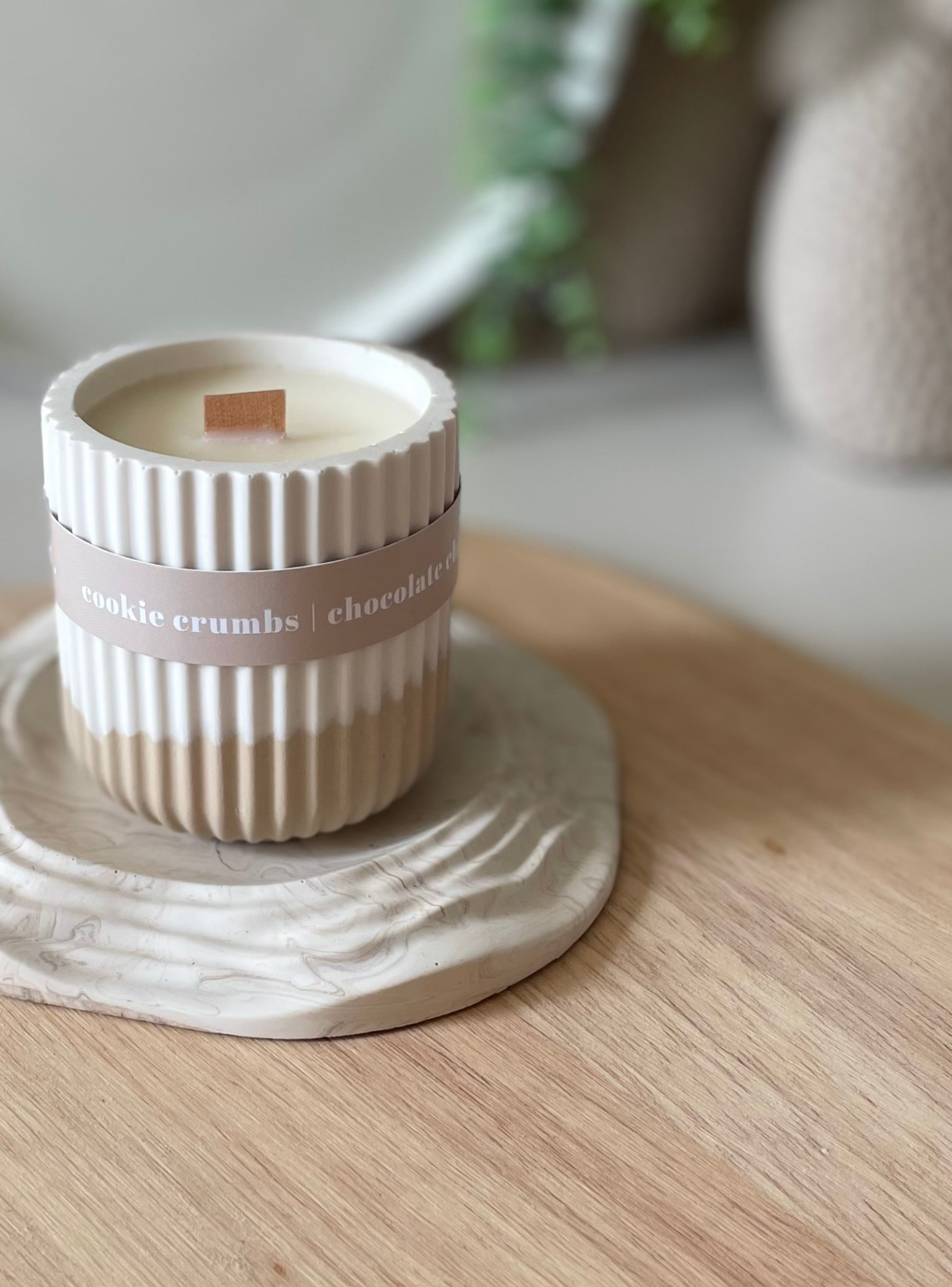 Candle in a decorative container on a wooden surface with a blurred background