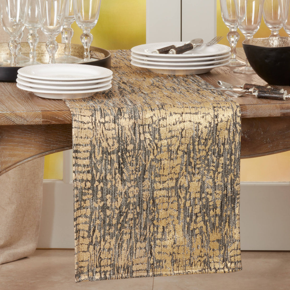 Dining table with a patterned table runner, plates, and glasses.