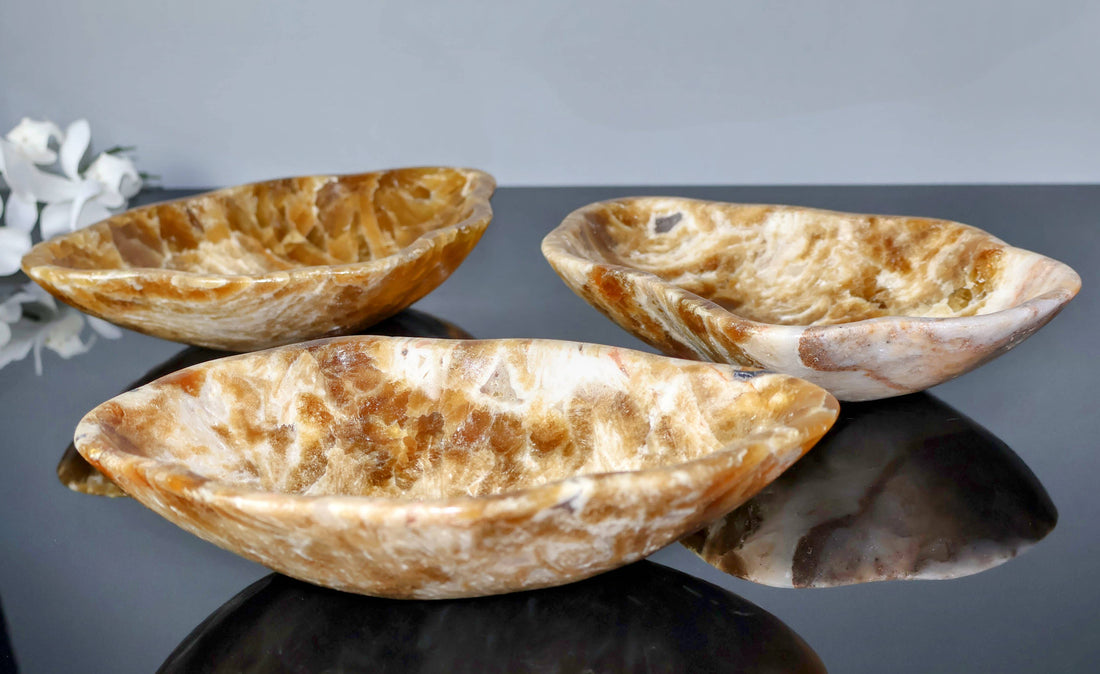 Three onyx bowls on a reflective surface with a gray background