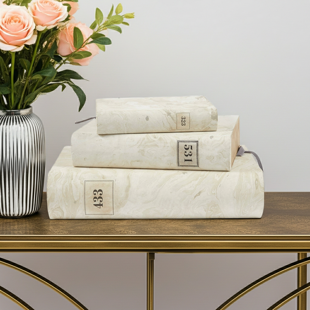 Stack of marble-like books on a wooden table with a vase of flowers.