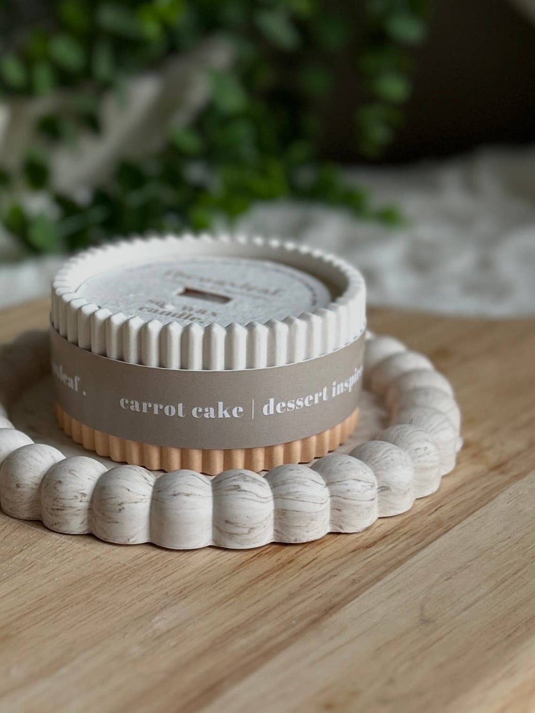 Round dessert container labeled 'carrot cake' on a wooden surface with a blurred natural background
