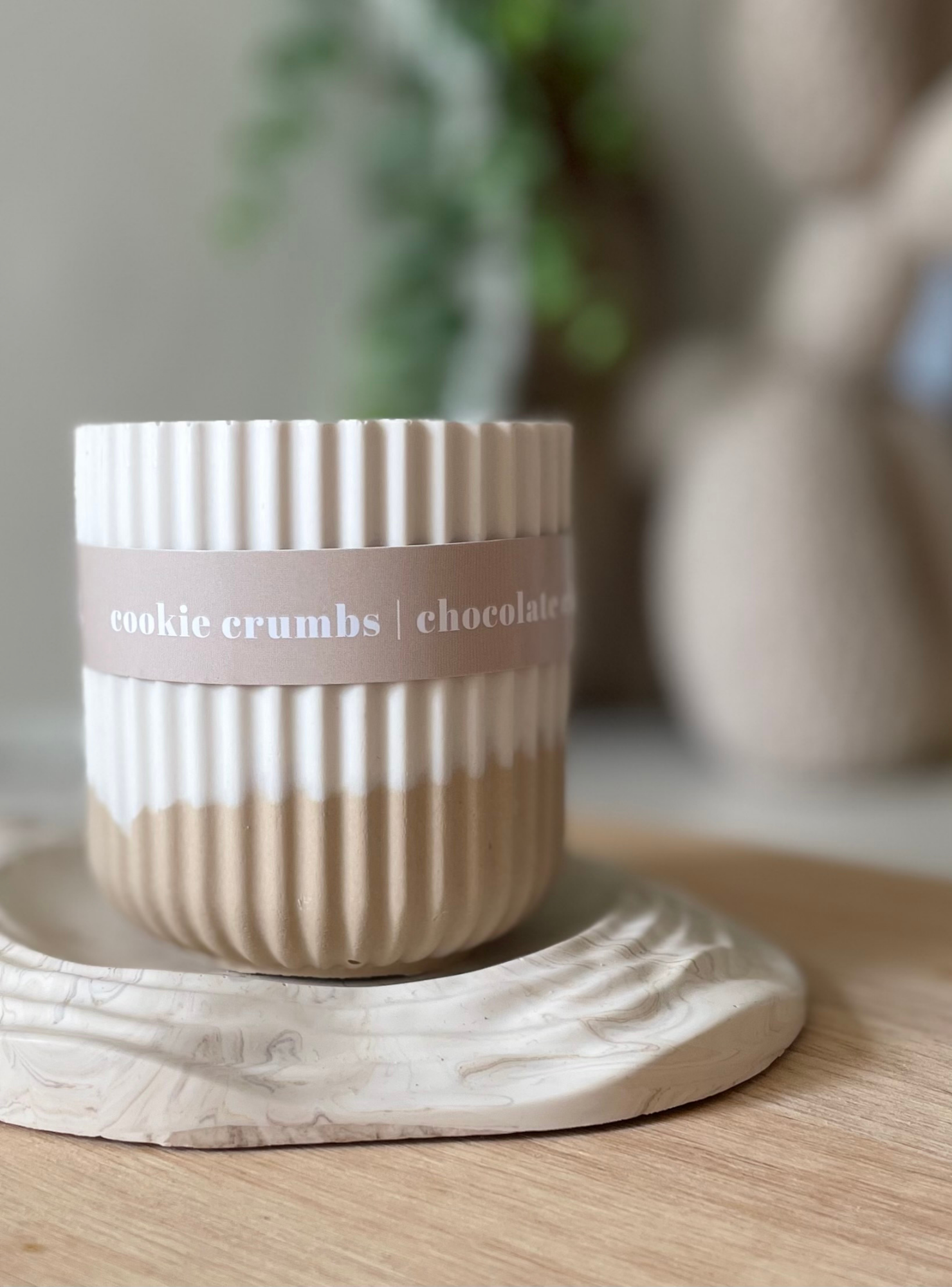 Ceramic container labeled 'cookie crumbs chocolate' on a wooden surface with a blurred background