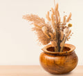Wooden vase with dried plants on a light background