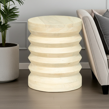 Decorative cylindrical side table with striped design in a living room setting.